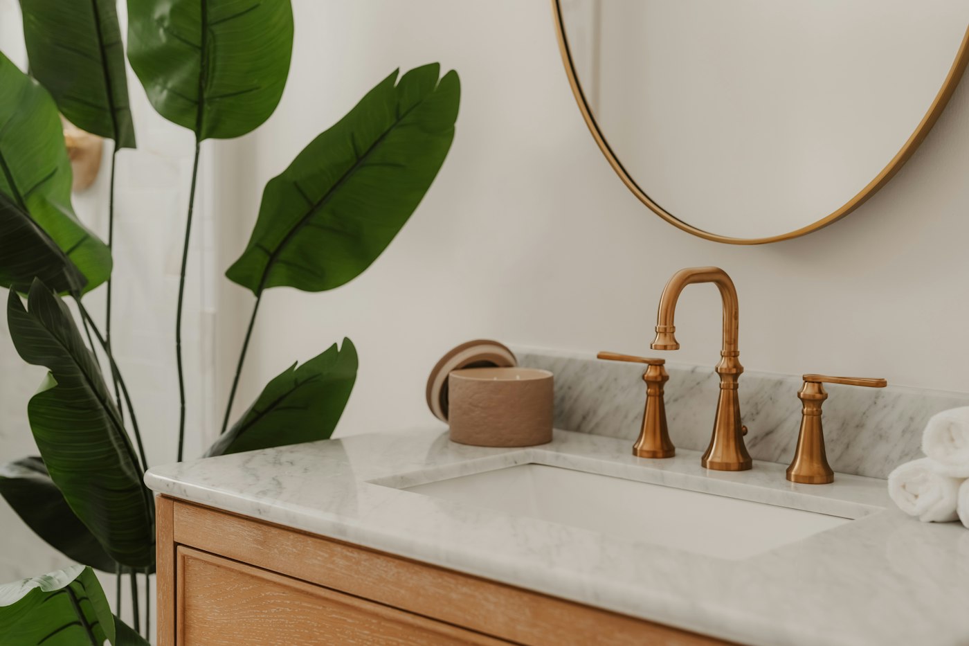 Marble bathroom sink with a brass faucet and green leaves.